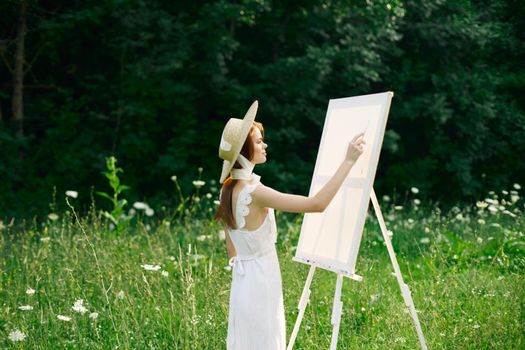 Woman in white dress in nature paints a picture of a landscape hobby. High quality photo