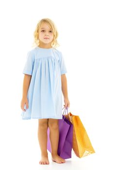 A cheerful little girl is shopping in a store with large, multi-colored paper bags. The concept of holidays, advertising sales. Isolated on white background.