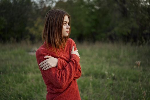 woman in a red sweater outdoors in the field nature rest. High quality photo