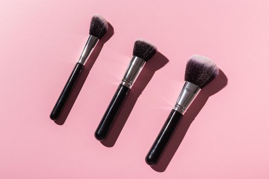 Various make-up brushes on pink background, top view. Cosmetics and beauty