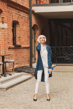 Portrait of young modern arabian woman holding mobile phone and listening the music to headphone