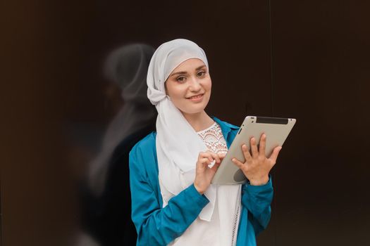 Beautiful Asian businesswomen wearing hijab using her tablet at outdoor.