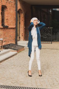 Portrait of young arabian muslim woman listening music with headphone and dancing. Feminism, woman independence and leisure concept