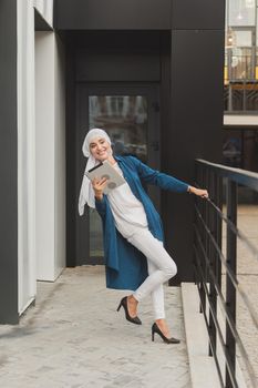 Modern Arabian muslim woman with tablet computer outdoors.