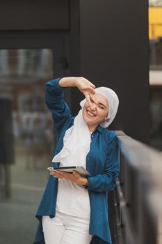 Modern Arabian muslim woman with tablet computer outdoors.