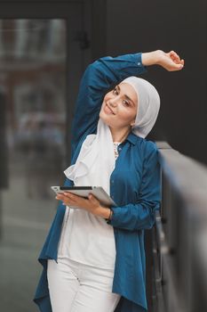 Young asian muslim woman in head scarf smile with mobile tablet.