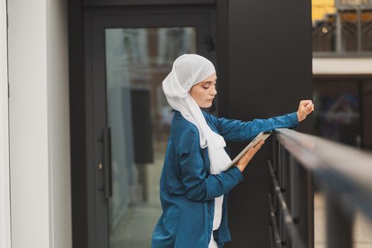 Young asian muslim woman in head scarf smile with mobile tablet.