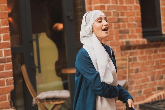 Portrait of young arabian muslim woman listening music with headphone and dancing. Feminism, woman independence and leisure concept