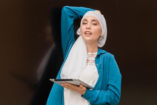 Young asian muslim woman in head scarf smile with mobile tablet.