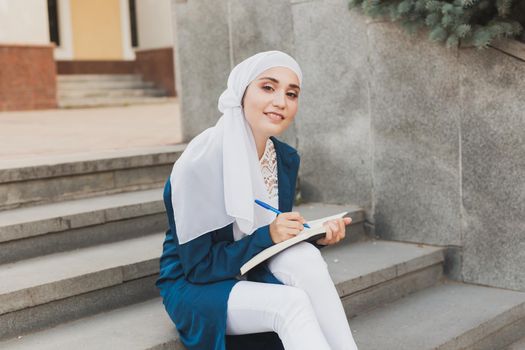 Arab female student sitting on stairs in downtown