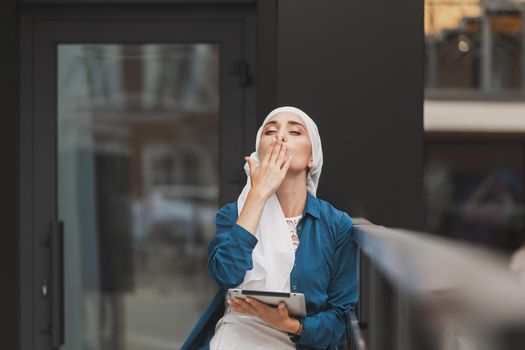 Beautiful Asian businesswomen wearing hijab using her tablet at outdoor.