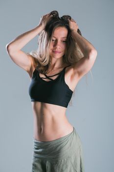Fitness and diet concept. Portrait of young woman with perfect sporty body and pretty flat abs in sexy sportswear top on gray background
