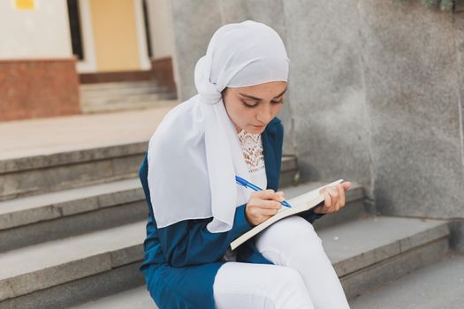 Arab female student sitting on stairs in downtown