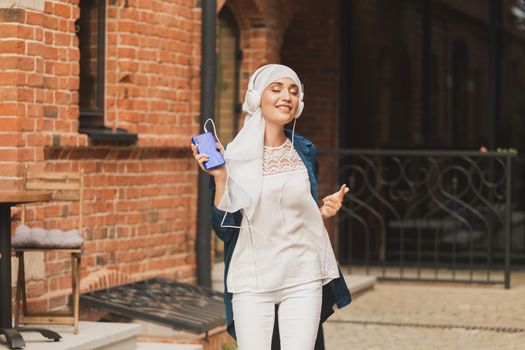 Portrait of young arabian muslim woman listening music with headphone and dancing. Feminism, woman independence and leisure concept