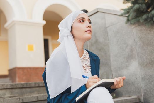 Arab female student sitting on stairs in downtown