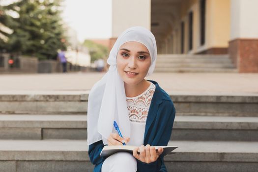 Arab female student sitting on stairs in downtown