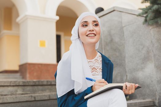 Arab female student sitting on stairs in downtown