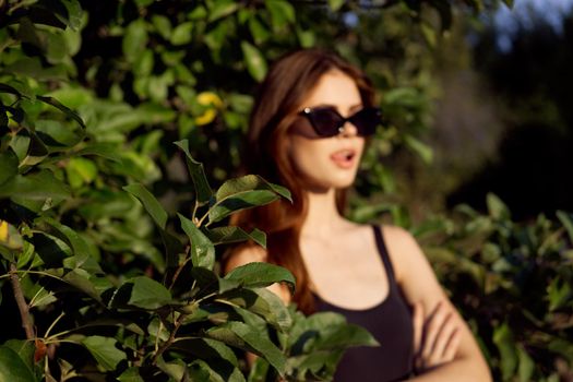 pretty woman in sunglasses in summer outdoors green leaves. High quality photo