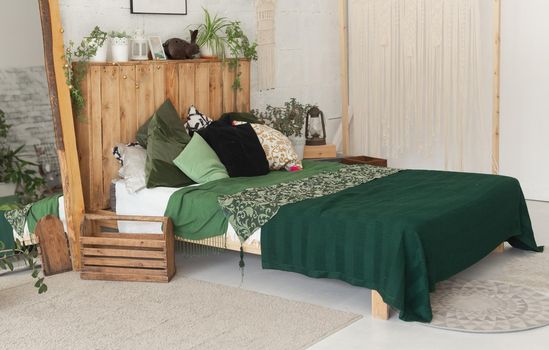 Comfortable bed with new green linens in eco style room interior.