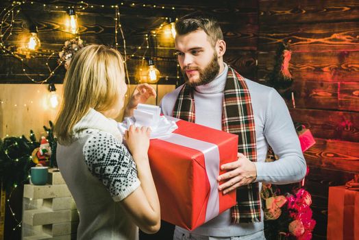 Young couple in love open Christmas gifts at home. New Year eve
