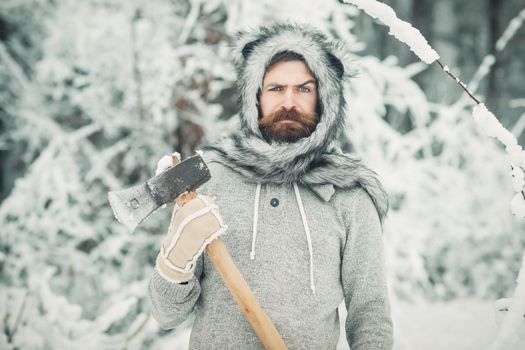 Winter bearded man lumberjack hold axe in snowy winter forest