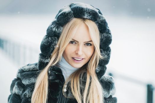 Girl on winter day. Woman Model in fur on snowy nature.