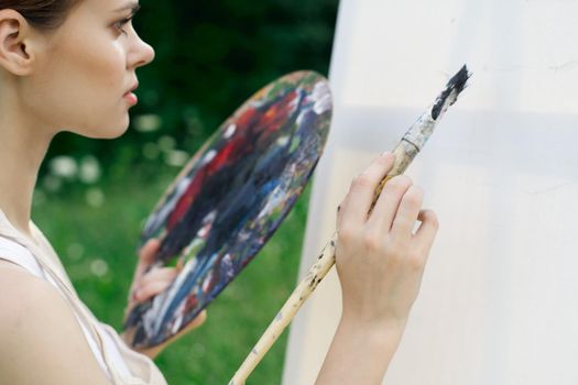 woman artist paints palette easel nature drawing. High quality photo