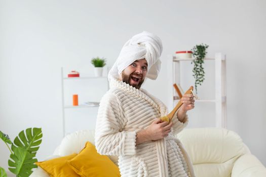 Funny handsome man pretends to play on massage brush as a guitar. Fun, spa and humor concept