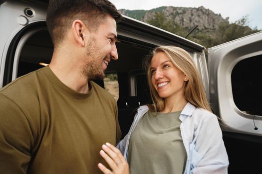 Young happy couple on a road trip sitting in car trunk outdoor