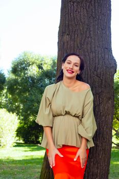 young pretty brunette pregnant woman outdoor in green park happy smiling, lifestyle people concept close up