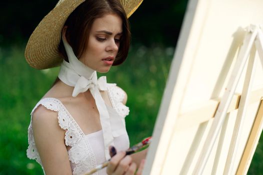 woman artist in hat with brush paints a picture. High quality photo