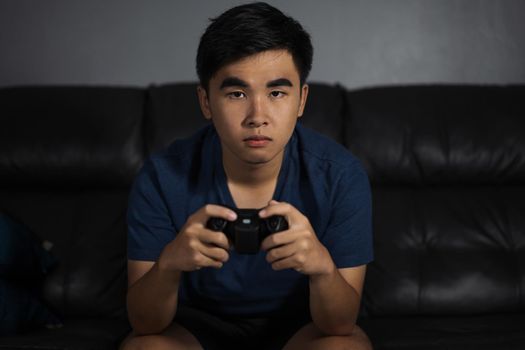 young man playing video game with joystick in the living room at night