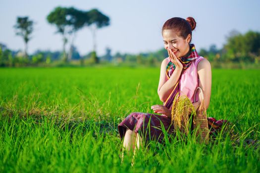 happy farmer woman sitting in green rice filed, Thailand