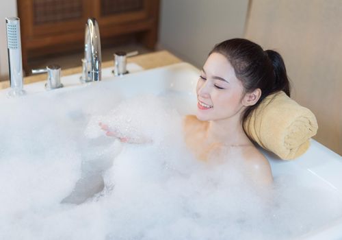 beautiful woman takes bubble bath and playing in bathtub