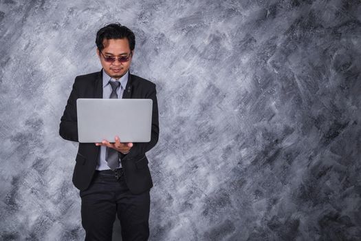 young business man holding laptop with wall background