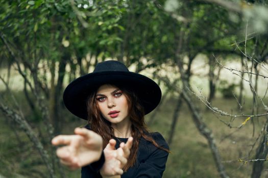 woman in a black hat gesturing with her hands witch magic fantasy. High quality photo