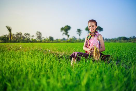 beautiful farmer woman sitting in green rice filed, Thailand