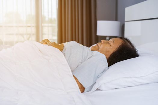 old woman sleeping on a bed in bedroom