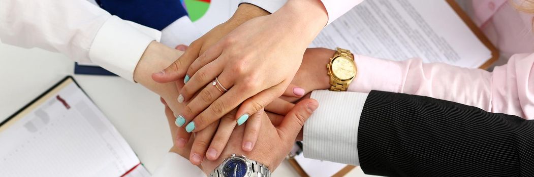 Group of people in suits crossed hands in pile for win closeup. White collar leadership, high five, cooperation initiative achievement, corporate life style, friendship deal, heap, stack concept