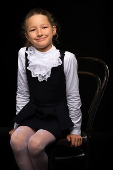 Beautiful little girl, studio portrait on a black background. The concept of a happy childhood, style and fashion.