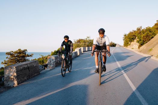 Two professional male cyclists riding their racing bicycles in the morning together on coastal road