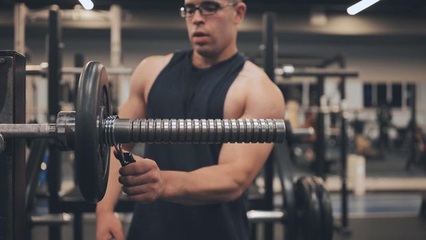 The male athlete changes the weight on the barbell
