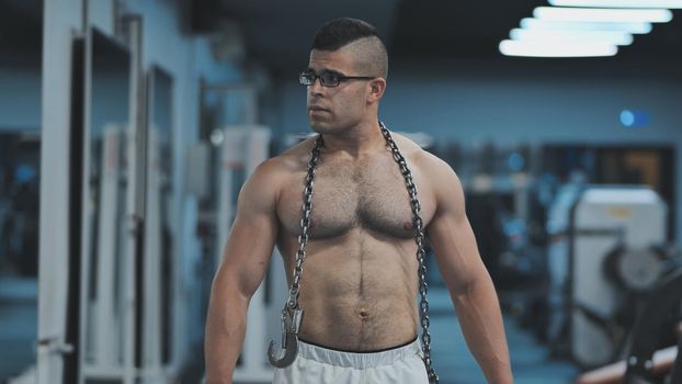 Muscular Arab in the gym walks with a metal chain after a workout