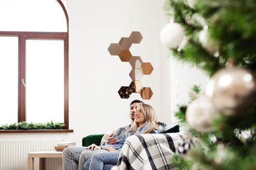 Sweet couple embracing on sofa at home during christmas holidays