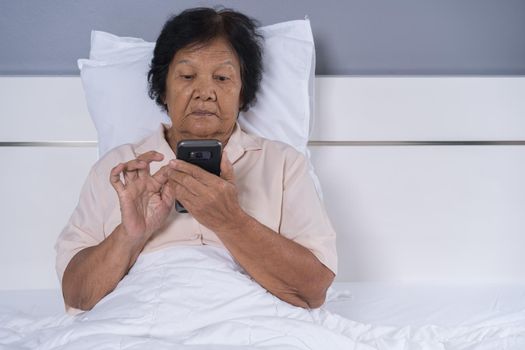 senior woman using mobile phone on a bed