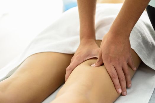 Medical massage at the leg in a physiotherapy center. Female physiotherapist inspecting her patient.