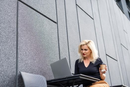 Cropped photo of a woman with laptop placed on the desk.