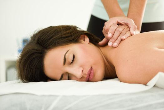 Young woman receiving a back massage in a spa center. Female patient is receiving treatment by professional therapist.