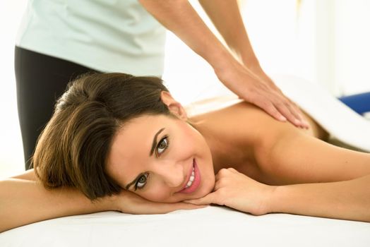 Young woman receiving a back massage in a spa center. Female patient is receiving treatment by professional therapist.