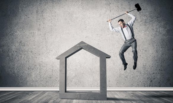 Determined businessman going to break with hammer house concrete figure